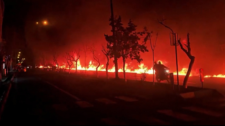 তেহরানের তেলের ডিপোতে ইসরায়েলি বিমান হামলার পর বড় আকারে আগুন ছড়িয়ে পড়ে। এই নারকীয় পরিস্থিতির মধ্যেই এক ব্যক্তি বাইক ছুটিয়েছেন সড়কে। ছবি: এএফপি 