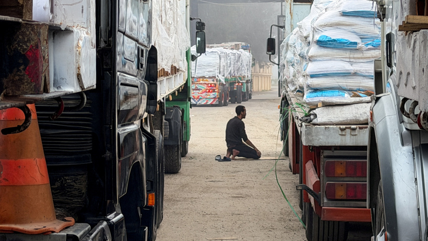 রাফা সীমান্তে সারি সারি ত্রাণবাহী ট্রাকের মাঝে নামাজ আদায় করছেন এক মিশরীয় ব্যক্তি। ছবি: 