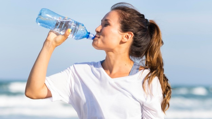 side-view-woman-drinking-water-beach-after-working-out_23-2148694943.jpg