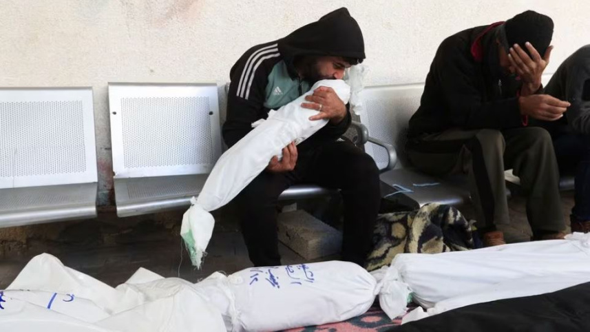 রাফাহর এক হাসপাতালে এক ব্যক্তি এক নিহত ফিলিস্তিনি শিশুর মরদেহকে চুম্বন করছেন। ছবি: রয়টার্স