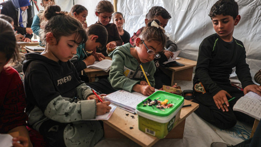 রাফায় তাঁবু খাটিয়ে অস্থায়ী স্কুল বানানো হয়েছে। সেখানে পড়াশোনা করছে ফিলিস্তিনি শিশুরা। ছবি: রয়টার্স
