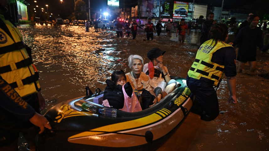 বন্যাকবলিত এক পরিবারকে উদ্ধার করছে উদ্ধারকর্মীরা। ছবি: এএফপি