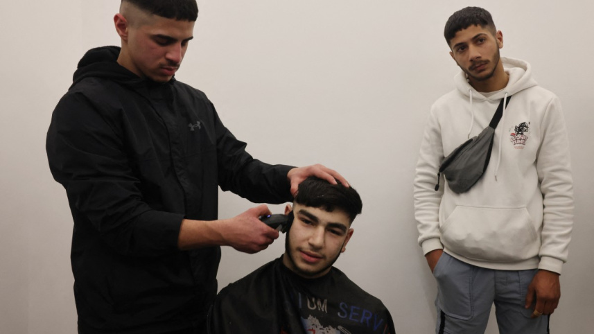 বাড়ি ফিরে নাপিতের কাছে চুল কাটাচ্ছেন ১৭ বছর বয়সী ফিলিস্তিনি কাশেম জাফরা। ছবি: এএফপি