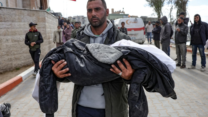 উত্তর গাজায় ইসরায়েলি বিমান হামলায় নিহত এক শিশুকে বহন করে নিয়ে যাচ্ছেন এক ব্যক্তি। ছবি: এএফপি