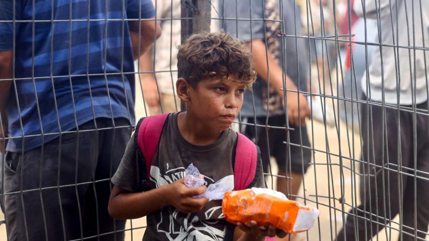 রাফায় ত্রাণকেন্দ্র থেকে মানবিক ত্রাণ পেয়েছে এক ফিলিস্তিনি শিশু। ছবি: এএফপি