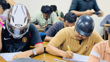 ছাদ থেকে খসে পড়ে পলেস্তারা, তাই হেলমেট পরে পরীক্ষা দিচ্ছেন শিক্ষার্থীরা। ছবি: স্টার