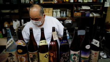 রেস্তোরাঁ বন্ধের আগে মদের বোতল সাজাচ্ছেন জাপানের এক রেস্তোরাঁ মালিক। ফাইল ছবি: রয়টার্স