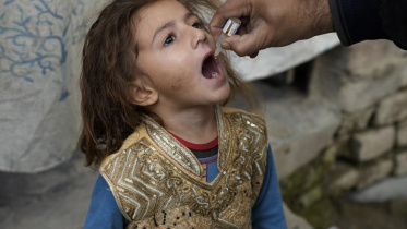 পাকিস্তানের এক শিশুকে পোলিওর ভ্যাকসিন খাওয়াচ্ছেন একজন স্বাস্থ্যকর্মী। ছবি: এপি