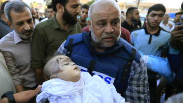 আল জাজিজার গাজা ব্যুরো প্রধান ওয়ায়েল দাদুহর তার এক নিহত সন্তানের লাশ বহন করছেন। ছবি: এএফপি