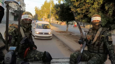 ইসরায়েলি জিম্মিদের মুক্তি দেওয়ার সময় হামাস যোদ্ধারা প্রহরা দেন। ছবি: রয়টার্স