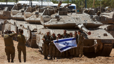 গাজা সীমান্তে ট্যাংকের সামনে দাঁড়িয়ে ছবি তুলছেন ইসরায়েলি সেনারা। ছবি: রয়টার্স