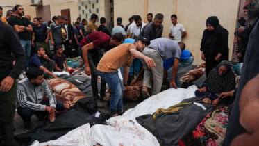 মধ্য গাজার নুসেইরাত শরণার্থী শিবিরের এই স্কুলে আজ সকালে ইসরায়েলি বোমা হামলায় ৩৭ জন নিহত হন। নিহতদের মরদেহ ঘিরে স্বজনরা শোক প্রকাশ করছে। ছবি: এএফপি