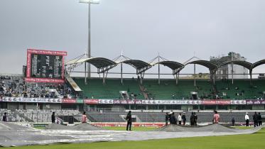 Members of ground staff cover the pitch at the Sher-E-Bangla National Cricket Stadium in Dhaka